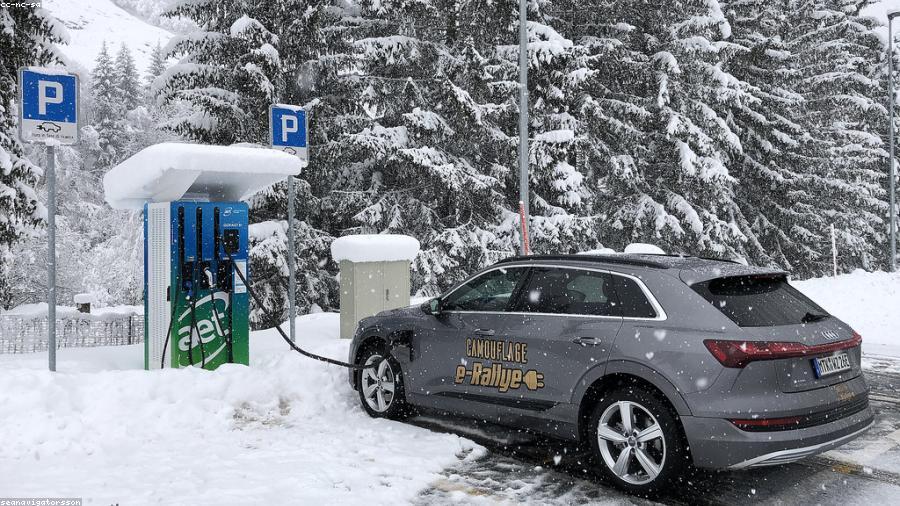 Elektroauto lädt an einer Schnellladestation bei Schneefall und winterlichen Bedingungen